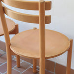 Paire de chaises vintage en hêtre massif, assise ronde et dossier à deux barreaux, style bistrot scandinave, présentées seules et en mise en situation.