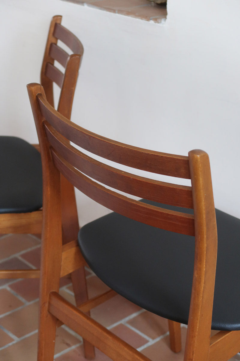 Paire de chaises scandinaves en teck avec dossier à lattes et assise en skaï noir, design danois des années 60.