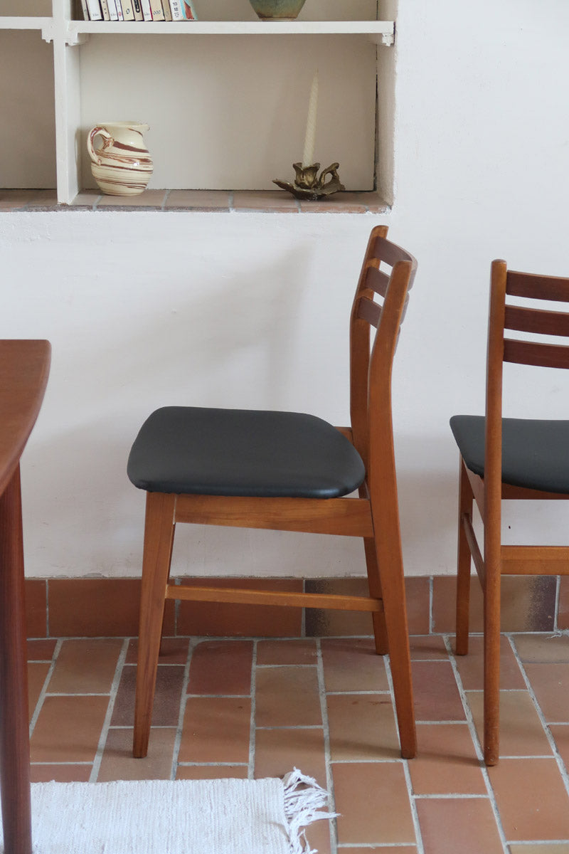 Paire de chaises scandinaves en teck avec dossier à lattes et assise en skaï noir, design danois des années 60.