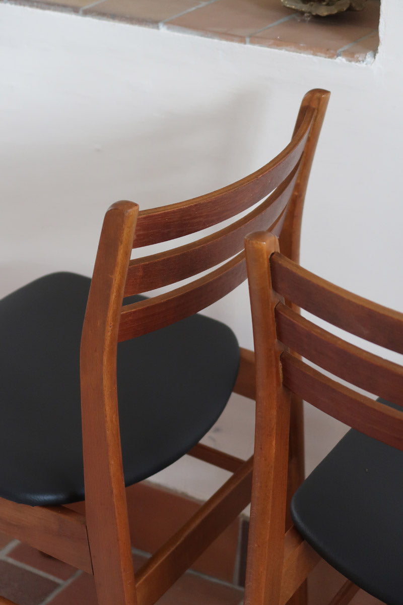 Paire de chaises scandinaves en teck avec dossier à lattes et assise en skaï noir, design danois des années 60.