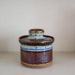 Pot couvert grès artisanal années 70, cylindrique, couvercle coupelle intégrée, bandes émail brun rouille blanc cassé moucheté liseré bleu cobalt