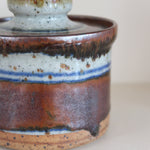Pot couvert grès artisanal années 70, cylindrique, couvercle coupelle intégrée, bandes émail brun rouille blanc cassé moucheté liseré bleu cobalt