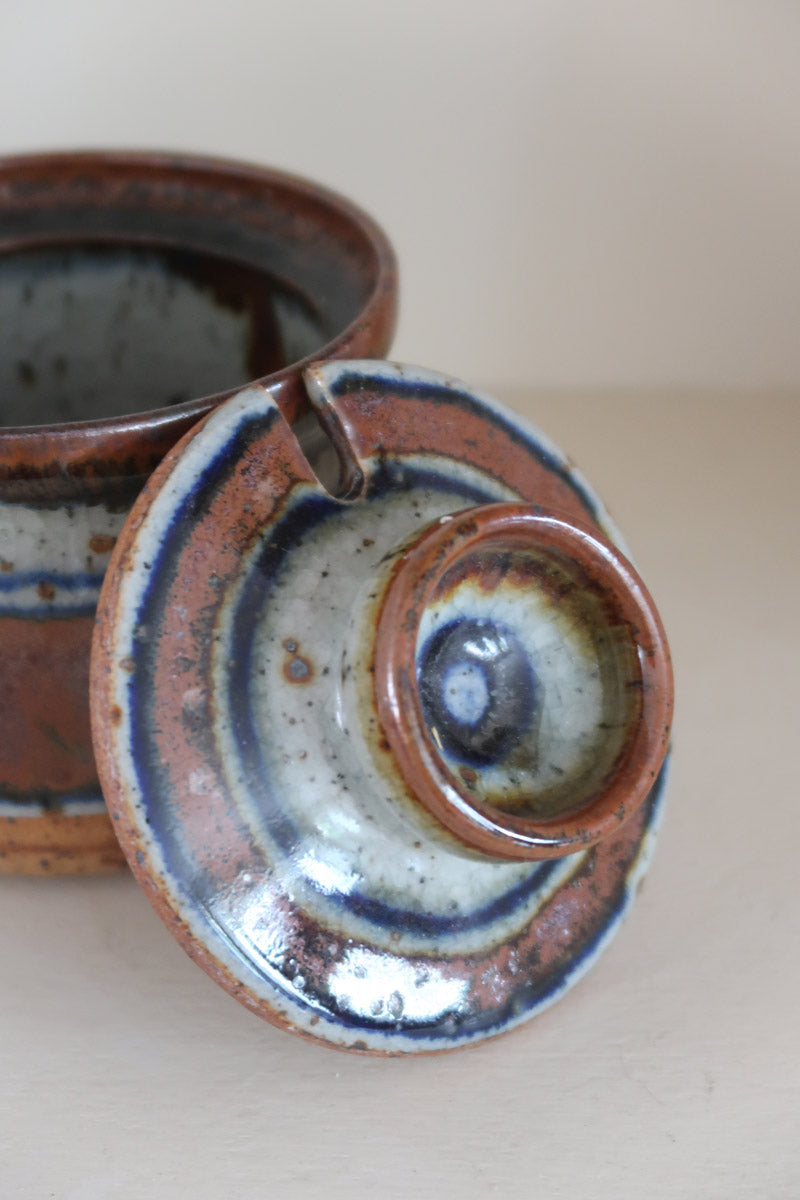 Pot couvert grès artisanal années 70, cylindrique, couvercle coupelle intégrée, bandes émail brun rouille blanc cassé moucheté liseré bleu cobalt