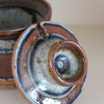 Pot couvert grès artisanal années 70, cylindrique, couvercle coupelle intégrée, bandes émail brun rouille blanc cassé moucheté liseré bleu cobalt