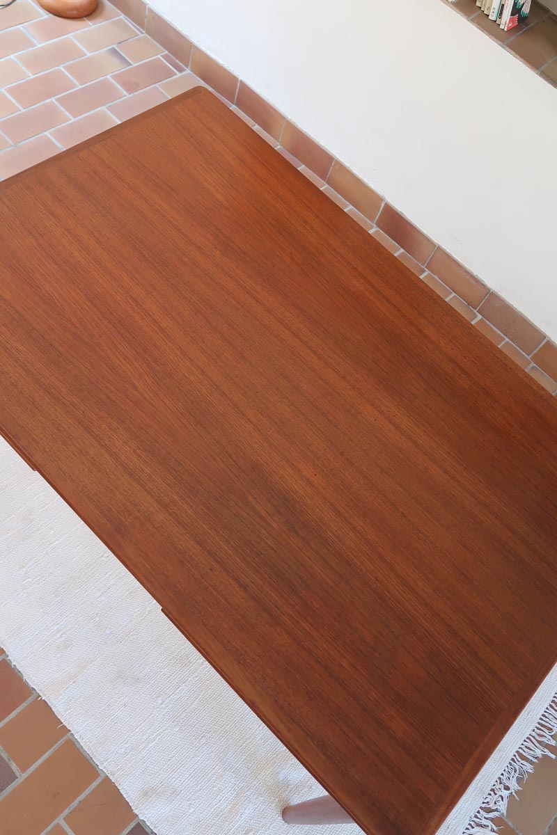 Table scandinave vintage en teck, années 60, extensible avec rallonge intégrée, pieds fuselés, quelques micro-rayures et pocs discrets visibles sur le plateau.