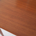 Table scandinave vintage en teck, années 60, extensible avec rallonge intégrée, pieds fuselés, quelques micro-rayures et pocs discrets visibles sur le plateau.