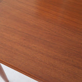 Table scandinave vintage en teck, années 60, extensible avec rallonge intégrée, pieds fuselés, quelques micro-rayures et pocs discrets visibles sur le plateau.