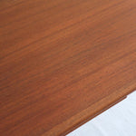 Table scandinave vintage en teck, années 60, extensible avec rallonge intégrée, pieds fuselés, quelques micro-rayures et pocs discrets visibles sur le plateau.