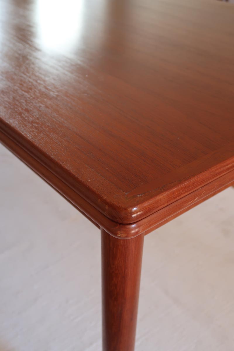 Table scandinave vintage en teck, années 60, extensible avec rallonge intégrée, pieds fuselés, quelques micro-rayures et pocs discrets visibles sur le plateau.