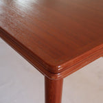 Table scandinave vintage en teck, années 60, extensible avec rallonge intégrée, pieds fuselés, quelques micro-rayures et pocs discrets visibles sur le plateau.