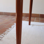 Table scandinave vintage en teck, années 60, extensible avec rallonge intégrée, pieds fuselés, quelques micro-rayures et pocs discrets visibles sur le plateau.