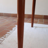 Table scandinave vintage en teck, années 60, extensible avec rallonge intégrée, pieds fuselés, quelques micro-rayures et pocs discrets visibles sur le plateau.