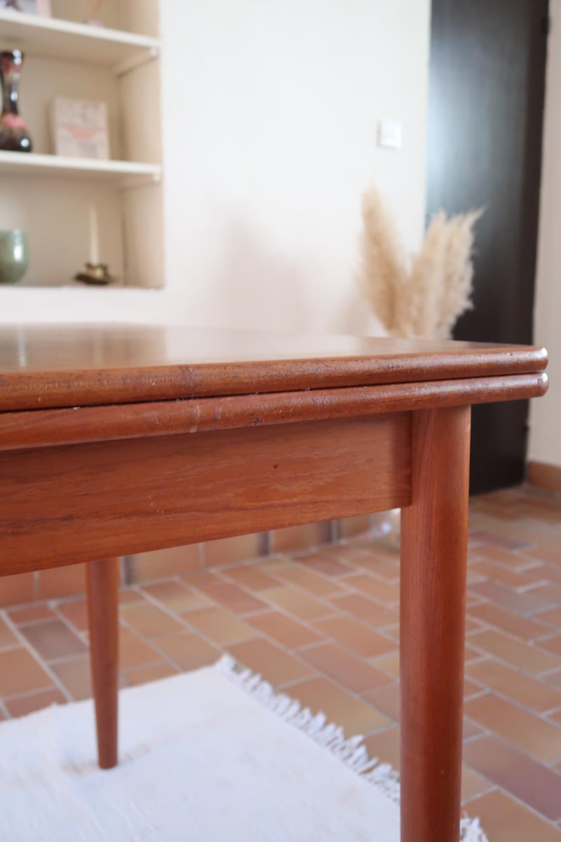 Table scandinave vintage en teck, années 60, extensible avec rallonge intégrée, pieds fuselés, quelques micro-rayures et pocs discrets visibles sur le plateau.
