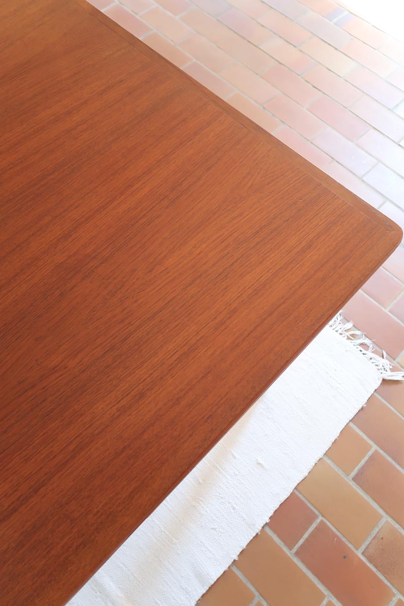 Table scandinave vintage en teck, années 60, extensible avec rallonge intégrée, pieds fuselés, quelques micro-rayures et pocs discrets visibles sur le plateau.