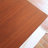 Table scandinave vintage en teck, années 60, extensible avec rallonge intégrée, pieds fuselés, quelques micro-rayures et pocs discrets visibles sur le plateau.