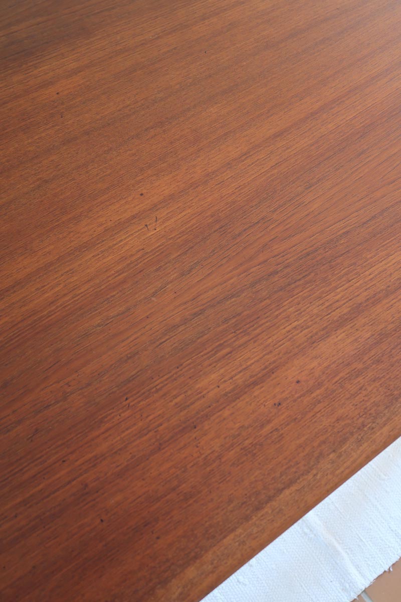 Table scandinave vintage en teck, années 60, extensible avec rallonge intégrée, pieds fuselés, quelques micro-rayures et pocs discrets visibles sur le plateau.