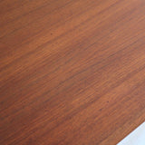 Table scandinave vintage en teck, années 60, extensible avec rallonge intégrée, pieds fuselés, quelques micro-rayures et pocs discrets visibles sur le plateau.