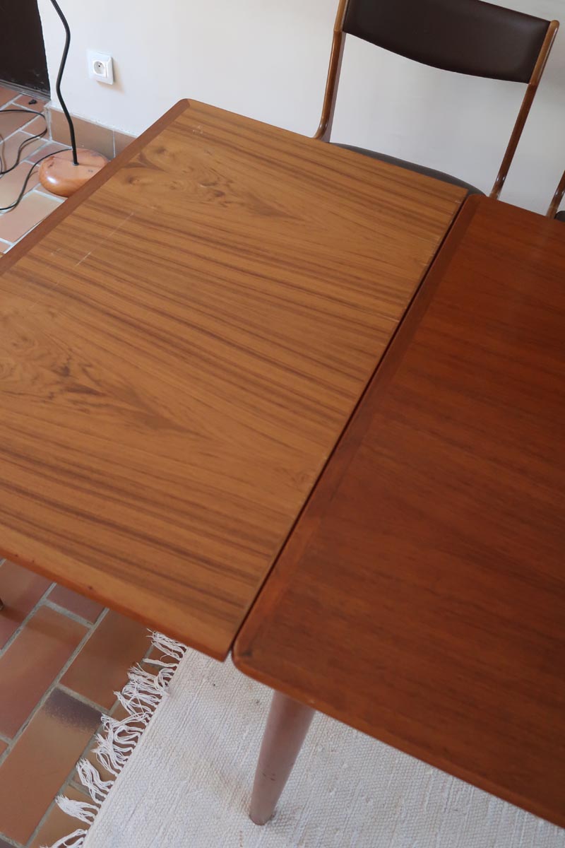 Table scandinave vintage en teck, années 60, extensible avec rallonge intégrée, pieds fuselés, quelques micro-rayures et pocs discrets visibles sur le plateau.