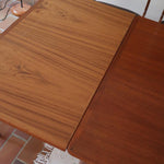 Table scandinave vintage en teck, années 60, extensible avec rallonge intégrée, pieds fuselés, quelques micro-rayures et pocs discrets visibles sur le plateau.