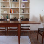 Table scandinave vintage en teck, années 60, extensible avec rallonge intégrée, pieds fuselés, quelques micro-rayures et pocs discrets visibles sur le plateau.