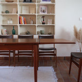 Table scandinave vintage en teck, années 60, extensible avec rallonge intégrée, pieds fuselés, quelques micro-rayures et pocs discrets visibles sur le plateau.