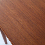 Table scandinave vintage en teck, années 60, extensible avec rallonge intégrée, pieds fuselés, quelques micro-rayures et pocs discrets visibles sur le plateau.