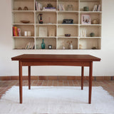 Table à manger scandinave extensible en teck, design danois des années 60, patine chaleureuse et traces du temps légères.
