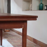 Table à manger scandinave extensible en teck, design danois des années 60, patine chaleureuse et traces du temps légères.
