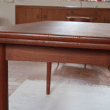 Table à manger scandinave extensible en teck, design danois des années 60, patine chaleureuse et traces du temps légères.
