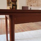 Table à manger scandinave extensible en teck, design danois des années 60, patine chaleureuse et traces du temps légères.
