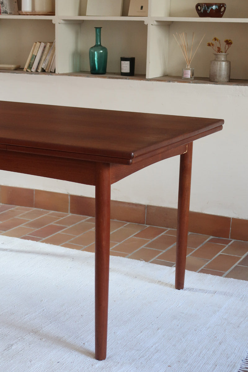 Table à manger scandinave extensible en teck, design danois des années 60, patine chaleureuse et traces du temps légères.
