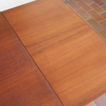 Table à manger scandinave extensible en teck, design danois des années 60, patine chaleureuse et traces du temps légères.
