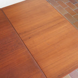 Table à manger scandinave extensible en teck, design danois des années 60, patine chaleureuse et traces du temps légères.
