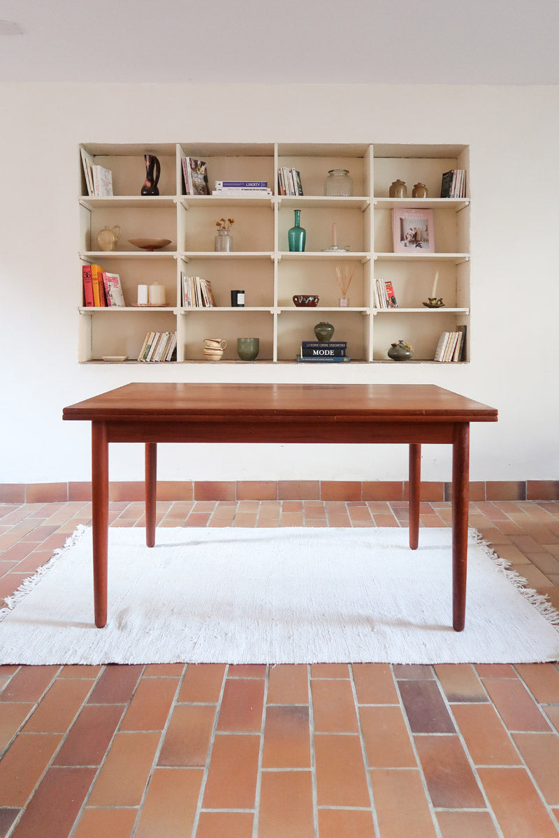 Table à manger scandinave en teck avec deux rallonges intégrées, design années 60, photographiée dans un intérieur lumineux.