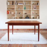 Table à manger scandinave en teck avec deux rallonges intégrées, design années 60, photographiée dans un intérieur lumineux.