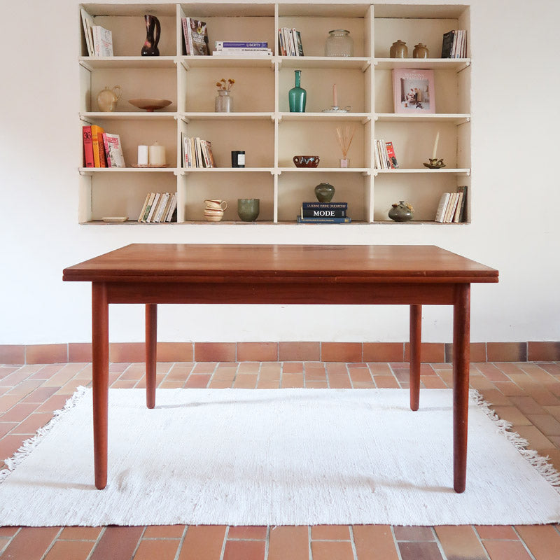 Table à manger scandinave en teck avec deux rallonges intégrées, design années 60, photographiée dans un intérieur lumineux.