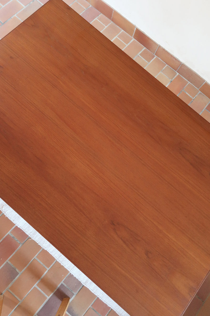 Table à manger scandinave en teck avec deux rallonges intégrées, design années 60, photographiée dans un intérieur lumineux.