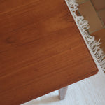 Table à manger scandinave en teck avec deux rallonges intégrées, design années 60, photographiée dans un intérieur lumineux.