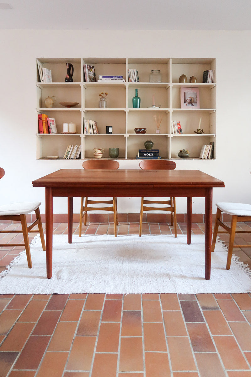 Table à manger scandinave en teck avec deux rallonges intégrées, design années 60, photographiée dans un intérieur lumineux.