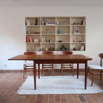 Table à manger scandinave en teck avec deux rallonges intégrées, design années 60, photographiée dans un intérieur lumineux.