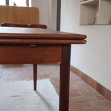 Table à manger scandinave en teck des années 60 avec deux rallonges intégrées et piètement fuselé.