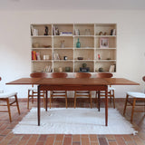 Table à manger scandinave en teck des années 60 avec deux rallonges intégrées et piètement fuselé.