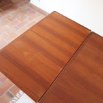 Table à manger scandinave en teck des années 60 avec deux rallonges intégrées et piètement fuselé.