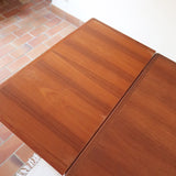 Table à manger scandinave en teck des années 60 avec deux rallonges intégrées et piètement fuselé.