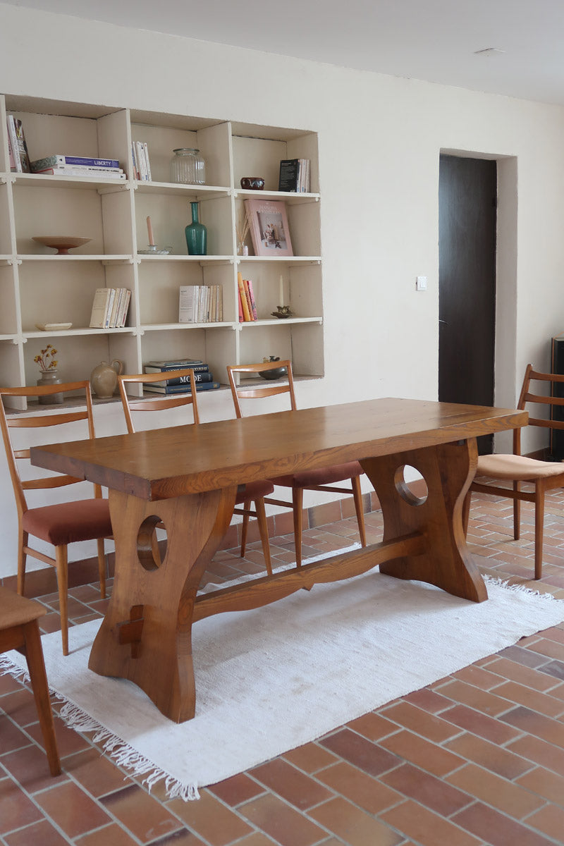 Table à manger vintage en bois massif années 60, plateau épais à chant brut, piétement traîneau sculpté, clé de tenon en croix, travail brutaliste français