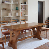Table à manger vintage en bois massif années 60, plateau épais à chant brut, piétement traîneau sculpté, clé de tenon en croix, travail brutaliste français