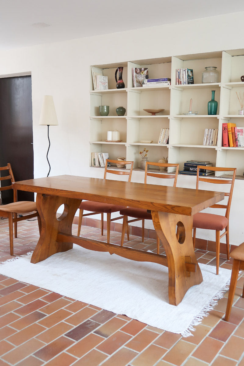 Table à manger vintage en bois massif années 60, plateau épais à chant brut, piétement traîneau sculpté, clé de tenon en croix, travail brutaliste français