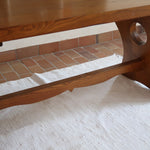 Table à manger vintage en bois massif années 60, plateau épais à chant brut, piétement traîneau sculpté, clé de tenon en croix, travail brutaliste français