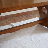 Table à manger vintage en bois massif années 60, plateau épais à chant brut, piétement traîneau sculpté, clé de tenon en croix, travail brutaliste français