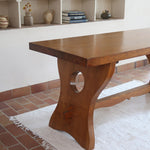 Table à manger vintage en bois massif années 60, plateau épais à chant brut, piétement traîneau sculpté, clé de tenon en croix, travail brutaliste français